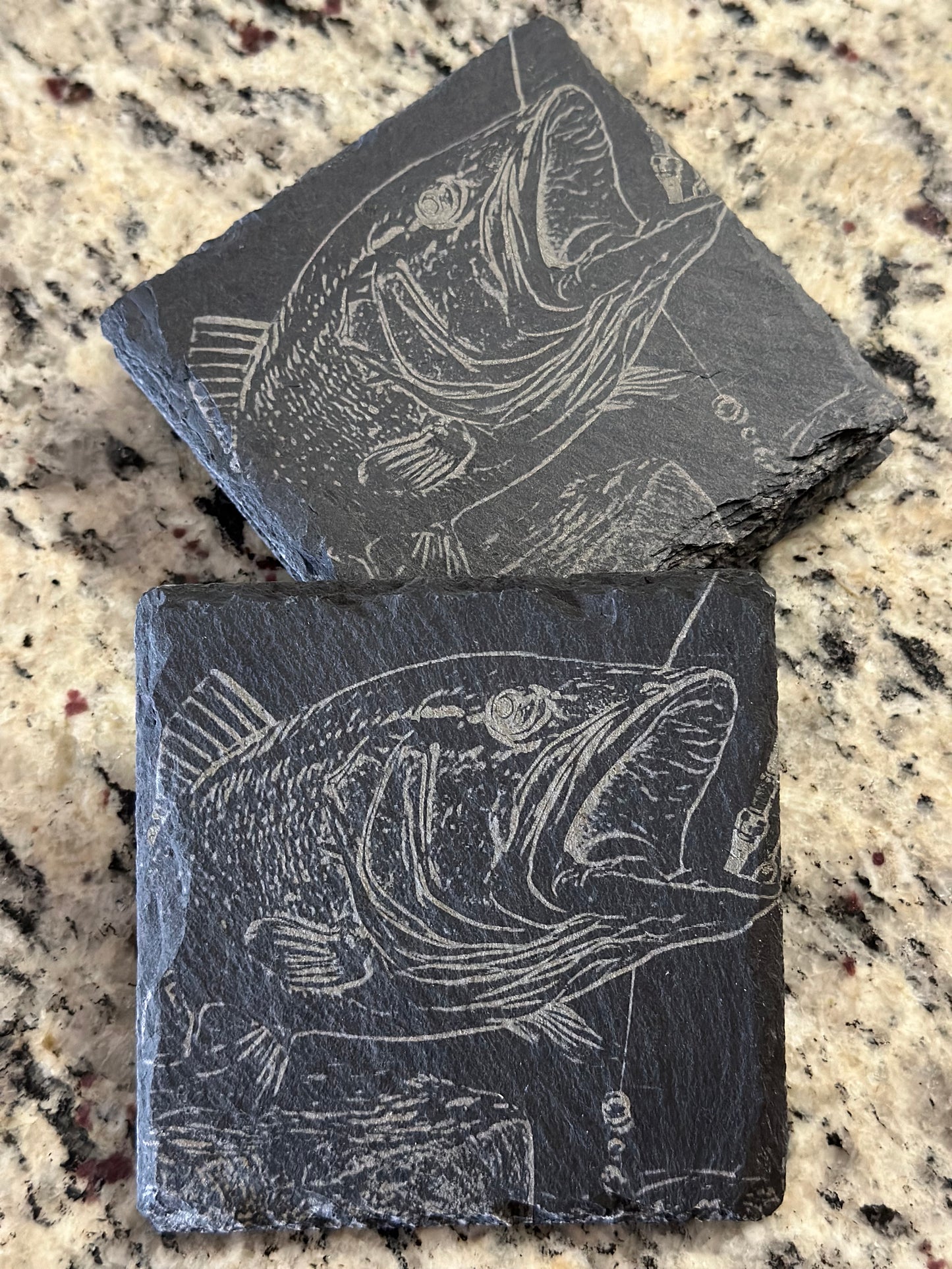 Engraved slate coasters with a detailed single big fish on a dark slate background.